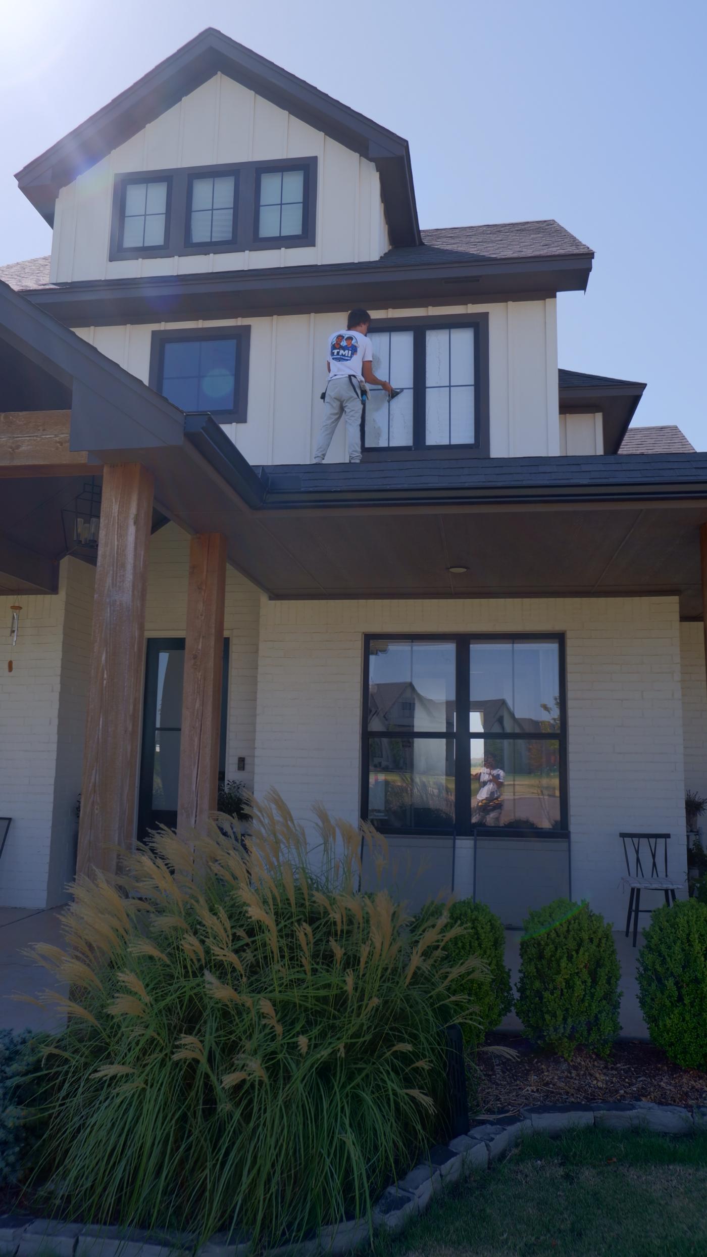 TMI crew member cleaning a dormer window from the roof